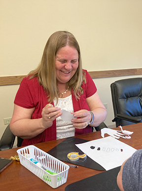 Julie Deden works on an art project involving paper cutouts.