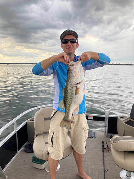 Standing on a boat, Justin Salisbury holds up an enormous fish.