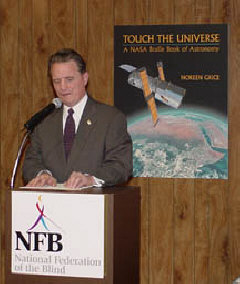 NFB President Dr. Murer welcomes guests and the media to the National Center for the Blind to celebrate NASA's release of Touch the Universe (poster on back wall depicts the book cover)