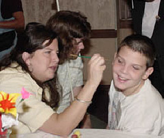 Face painting is one of the more popular booths at the convention's Braille Carnival.    At the 2002 Braille Carnival, Zack Erickson of Georgia tries to hold still while Jennifer Smith paints his name in Braille dots,
