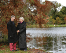A senior couple having a serious discussion beside a peaceful pond.