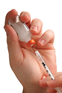 Hand filling a syringe with insulin.