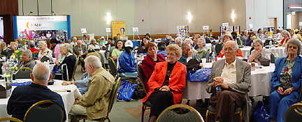The 2005 Possibilities Fair for seniors losing vision took place May 12 in Members Hall at the Jernigan Institute.   Here attendees settle back to listen to luncheon program speakers.   Exhibitor display boards are visible in the background.