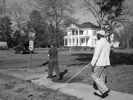 Instructor Roland Allen stays close enough to Adam Shaible at the intersection to be sure what he is doing. Behind them as they wait to cross the street can be seen one of the lovely old homes of Ruston.