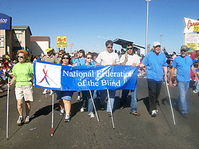 Members of the NFB of New Mexico march in the parade behind their banner.