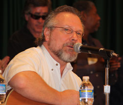 Brian Burns playing his guitar and singing at the opening convention session