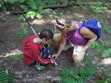 Thirteen-year-old Science Camp student Steven Crouch investigates soil in a wetland marsh with the help of Karen Taylor, a biology teacher and a science educator volunteer.