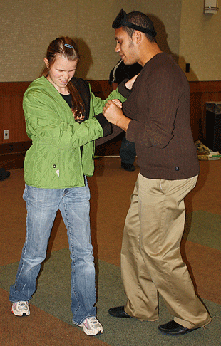 Alex Castillo (NY) teaches Victoria Trussell (GA) to dance the salsa. Alex identifies foot positions in the steps by using the dot positions in the Braille cell.