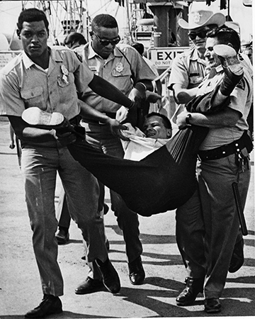 Russell Kletzing presses for the right to enjoy an amusement park as four security guards forcibly remove him.