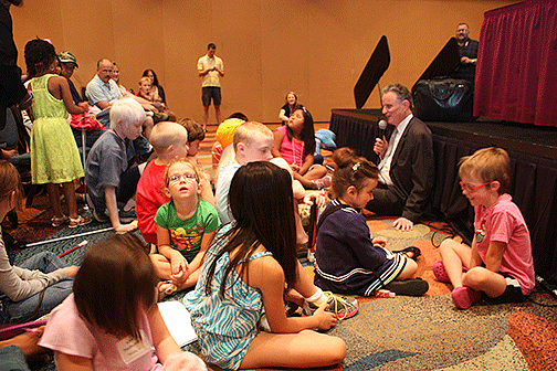 President Maurer sits on the floor with children at the start of the 2013 convention