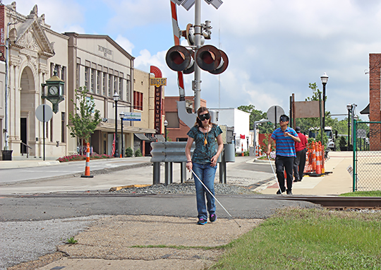 Participants in the program cross railroad tracks under sleepshades using a long white cane.