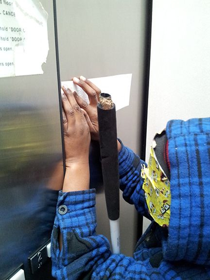 Trainee under sleepshades reads Braille in an elevator.