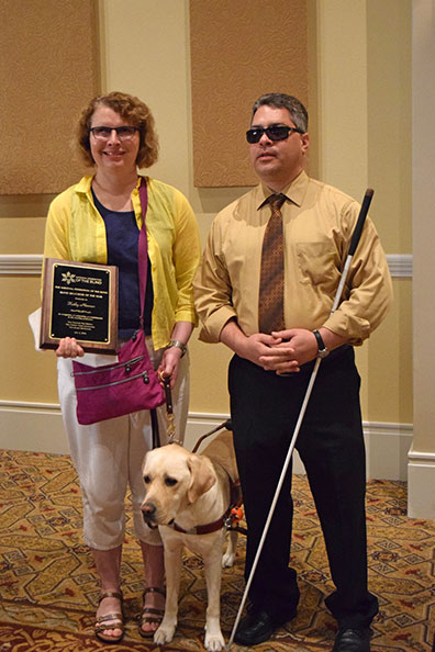 Kathy Nimmer poses next to Edward Bell holding her plaque.