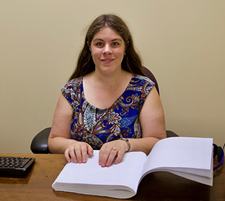 Chris Parsons sits at her desk reading Braille