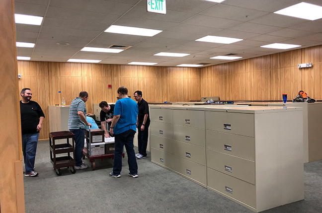 Staff members smile as they remove file boxes from a cart to be refiled in the new records center.