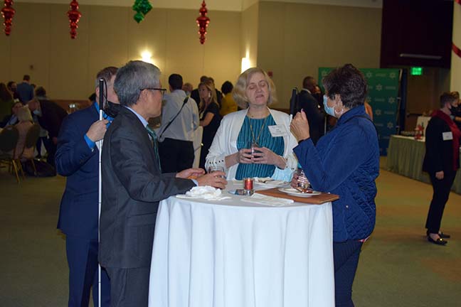 Patti Chang speaks with several supporters around a high top table.