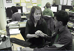 Denise Robinson signs into a student's right hand. With his left hand the student reads from a Braille display.