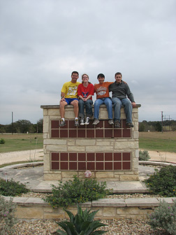 At the launch of the Texas CHANGE Program, two mentors with mentees on a stone structure surrounded by flowers.