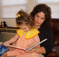 Kendra touches the Braille on the page as her mother reads to her from a print/Braille book. 