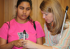 Mary Jo Hartle shows young teen how to position her hand on her cane.