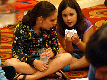 Two girls play a game on the floor.