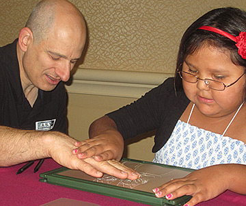 A girl explains her picture to E.A.S.Y.'s Mike Coleman as he examines it with his fingers.