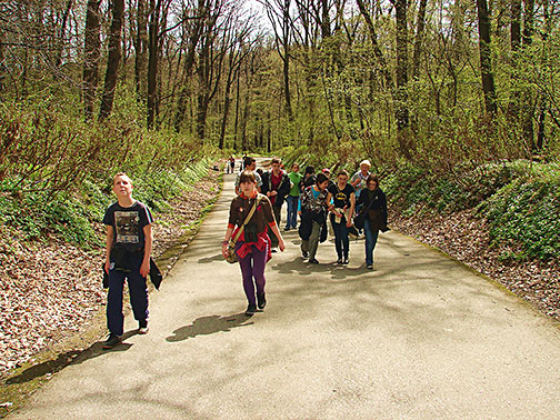 Przemyslaw Barszcz walks with a group of teens in the spring forest.