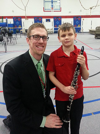 Christopher holds his clarinet with his teacher beside him.