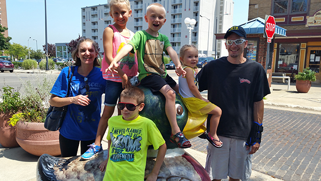 The Roberts children perch on a duck sculpture while their parents look on.