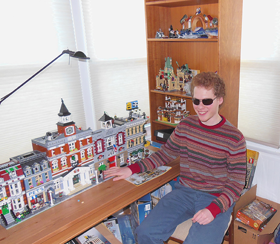 Matthew Shifrin sits at a table with a LEGO town.