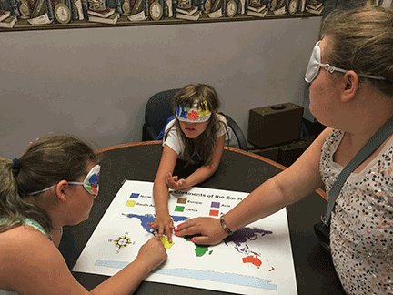Adison, Jazmin, and Meridian examine a tactile map under sleepshades at the Pittsburgh BELL Academy.