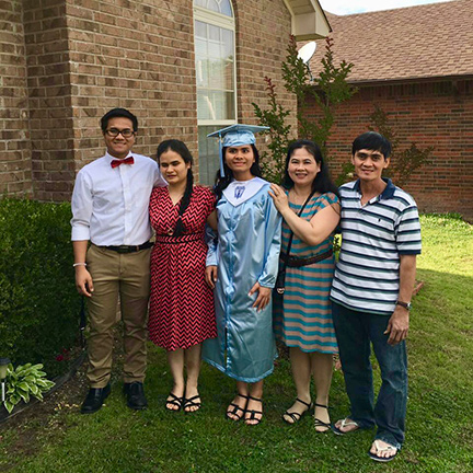Surrounded by her family, Trinh Ha stands in her cap and gown at her high school graduation.