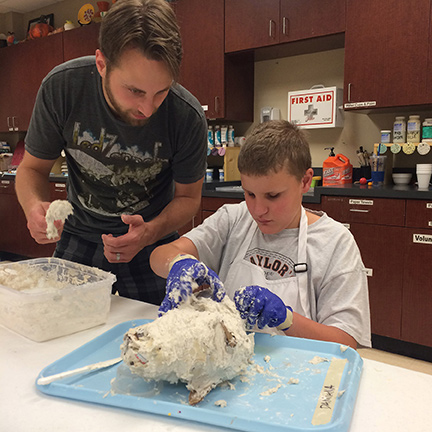 A boy creates the head of a deer with papier m&acirc;ch&eacute;.
