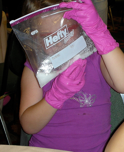 A girl holds a bag fizzing with Alka-Seltzer.