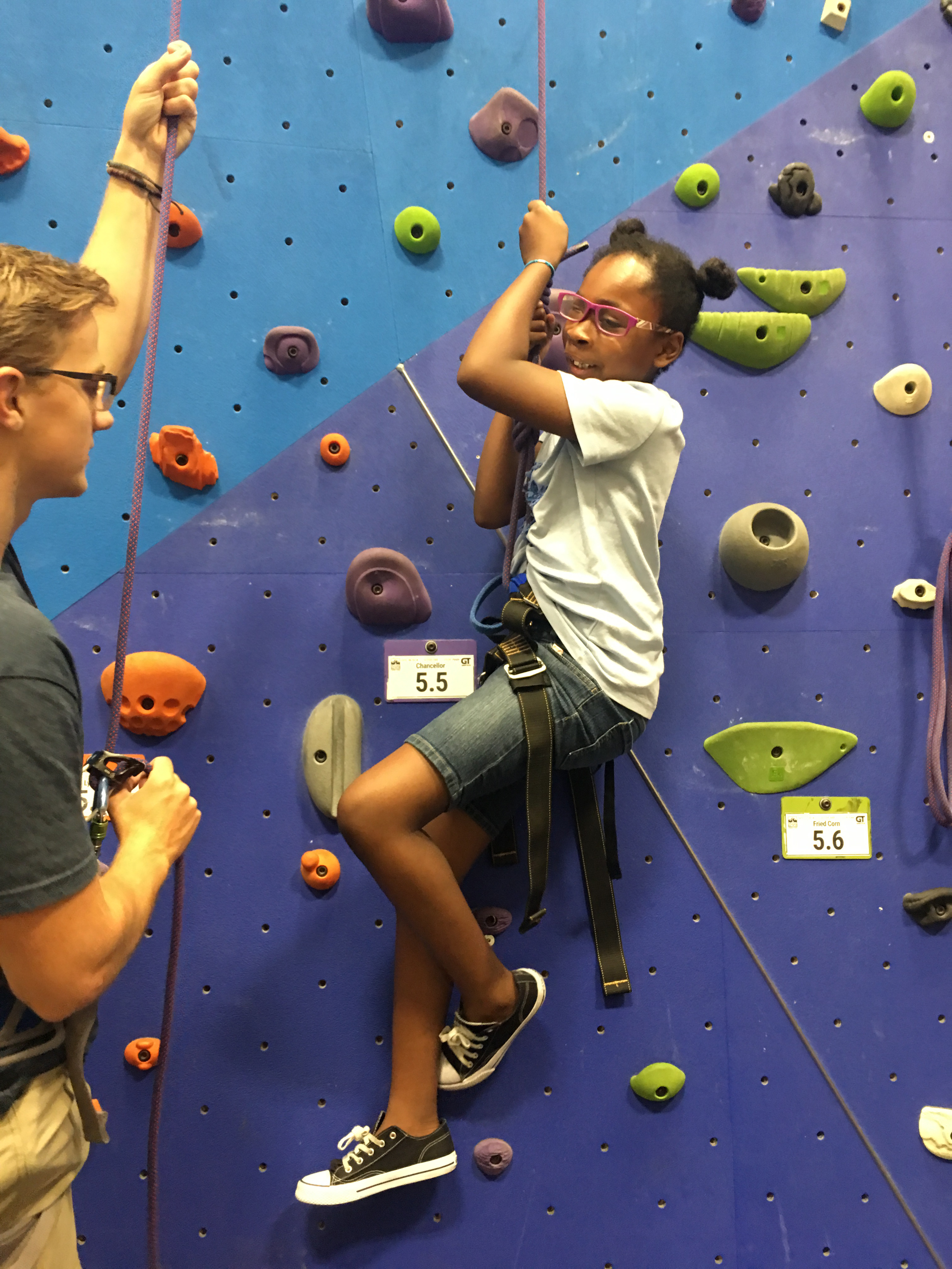 An instructor helps Brielle, a DC BELL participant, on a climbing wall.