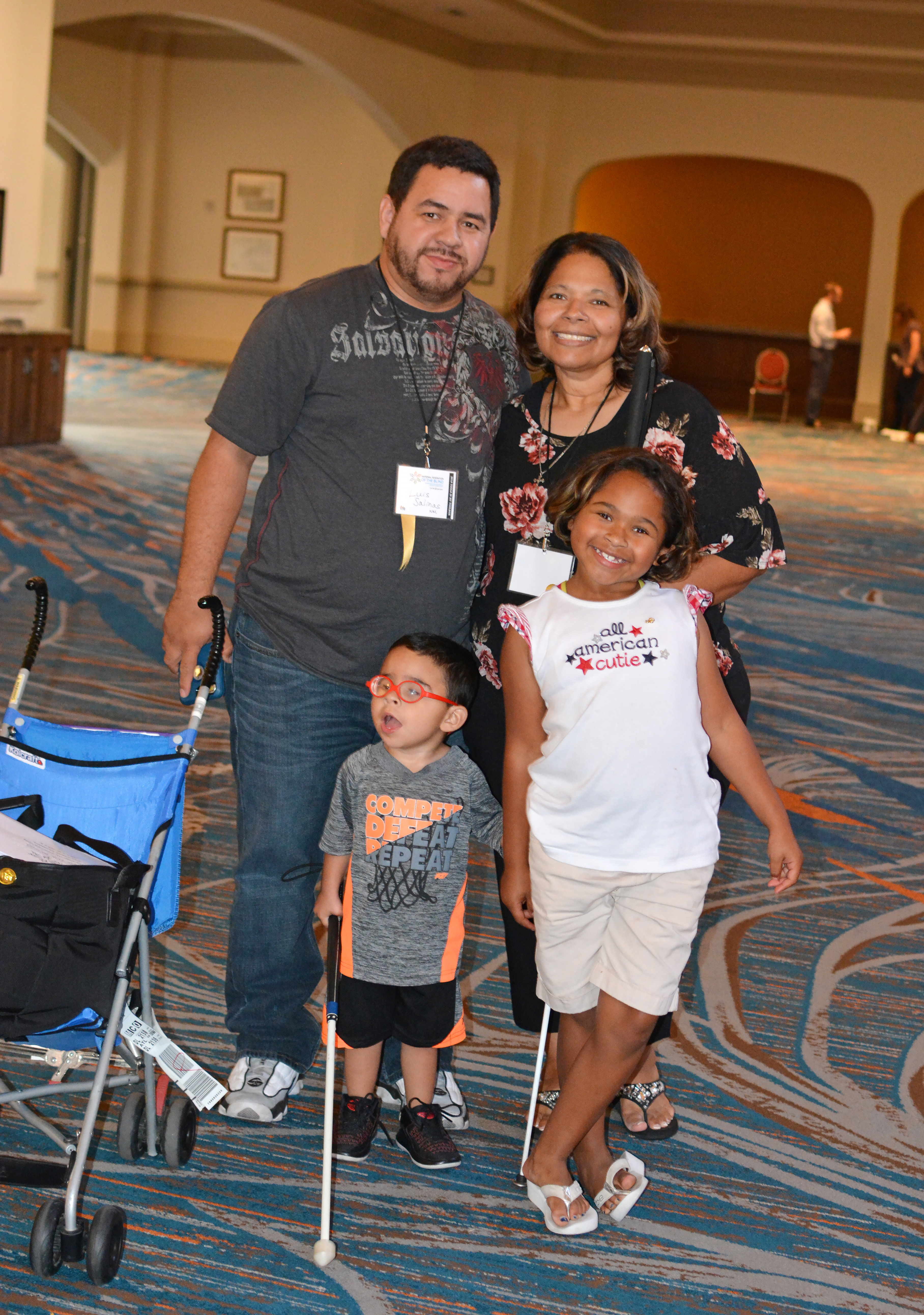 Luis and Virginia Salinas-Gutierrez and their children, Mario and Giada, stand in a hallway at the convention hotel. Virginia and Mario have long white canes.