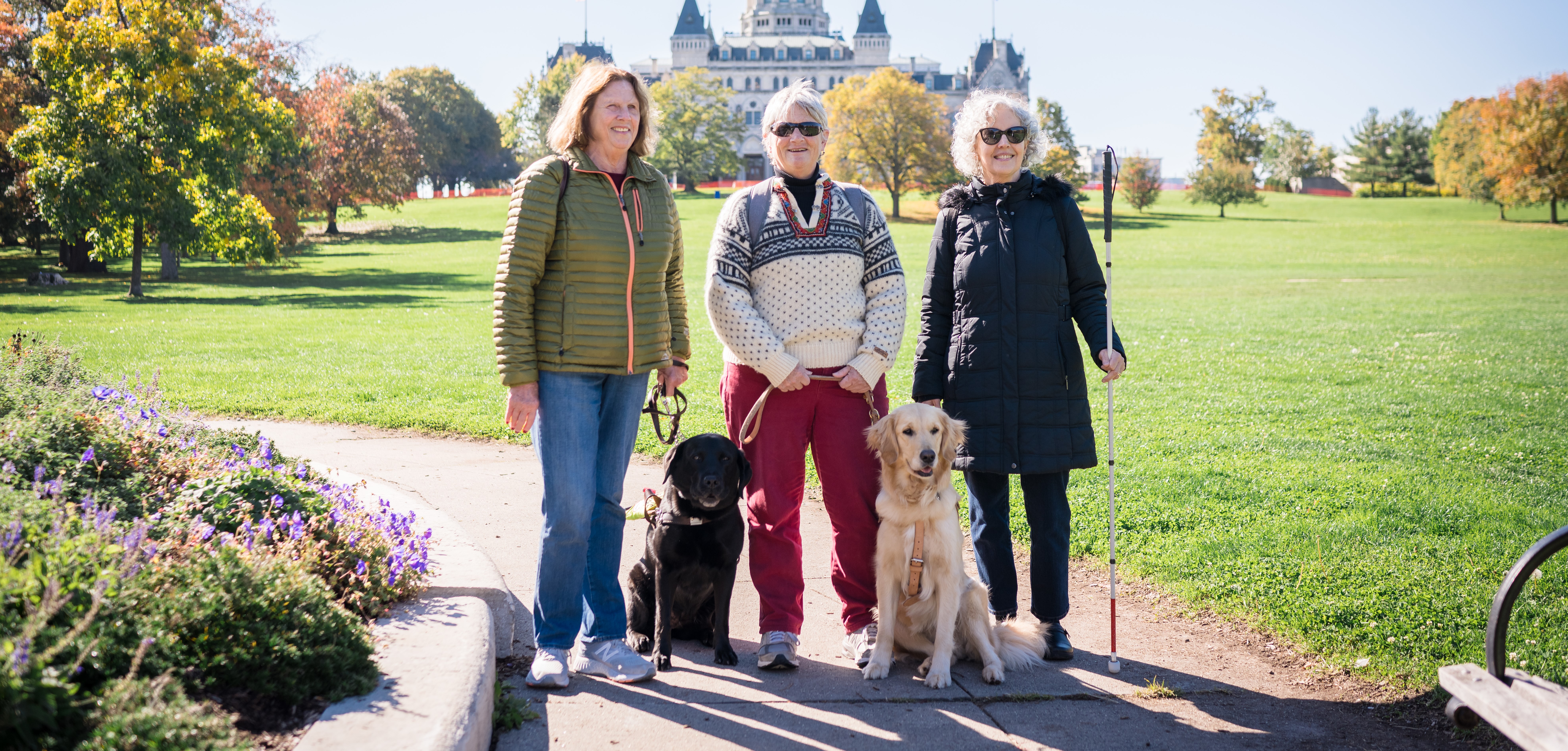 Three blind women stand in front of a park