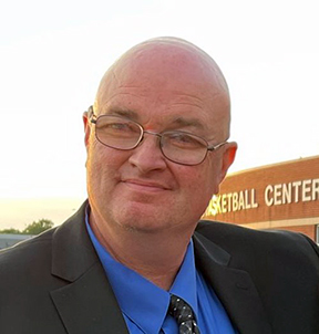 Head and shoulders shot of Todd Elzey standing outside dressed in a dark suit.