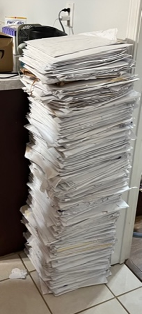 A large stack of paper that is taller than the counter next to it