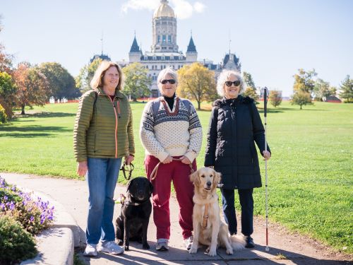 Three blind woman stand smiling in the park