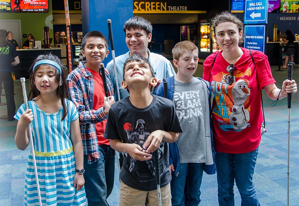 Blind children smile in front of a movie theater concession stand
