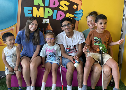 Three NFB BELL participants smile for a photo with their mentors while on a field trip to the Kids Empire.