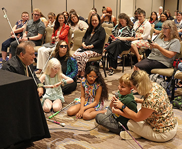 Mark Riccobono bends down to chat with three young blind children at our NFB National Convention.