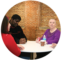 Three blind adults sit at a table having conversation.