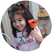 A young blind BELL participant smiles and rings her bell.