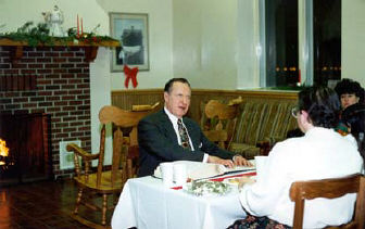 Dr. Jernigan sits reading Braille.   Several people can be seen listening. 