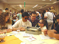 Eileen Kelly, Joe Portillo, Ryan Osentowski, and Timothy Kellt are seated at a Braille carnival table with a Brailler.