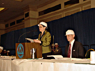Mary Ellen Jernigan at the podium with President Maurer beside her, both wearing hard hats