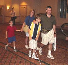 The Ryan Family from New Jersey walk down a hall at convention.   They are younger brother James, mother Valerie, Conner using his cane, and father Edward