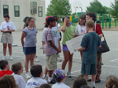 One of the seven students holds the cedrtificate Mrs. Maurer has just presented, and another examines a picture of the National Research and Training Institute.